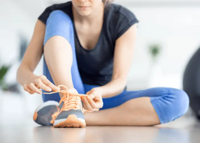 Mujer preparándose para hacer ejercicio poniéndose una zapatillas de deporte