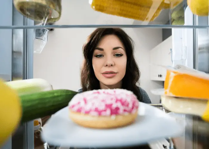chica ansiando comerse un donut en el frigorífico
