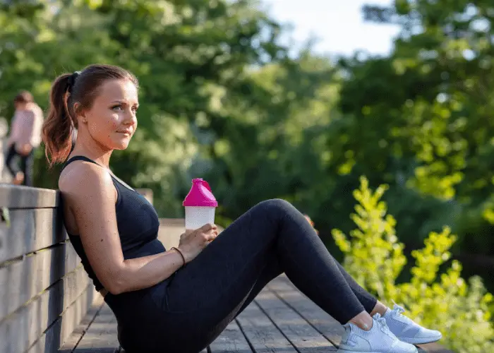 mujer fitness sentada en un banco con protein shake 